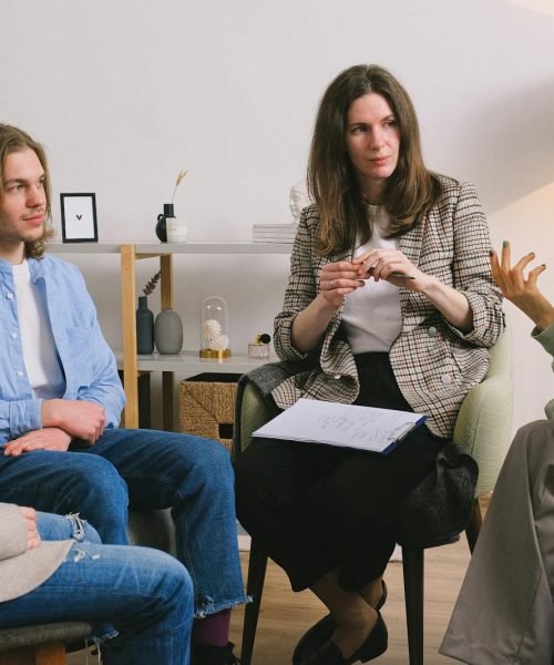 A group therapy session taking place indoors with an attentive counselor guiding the discussion.