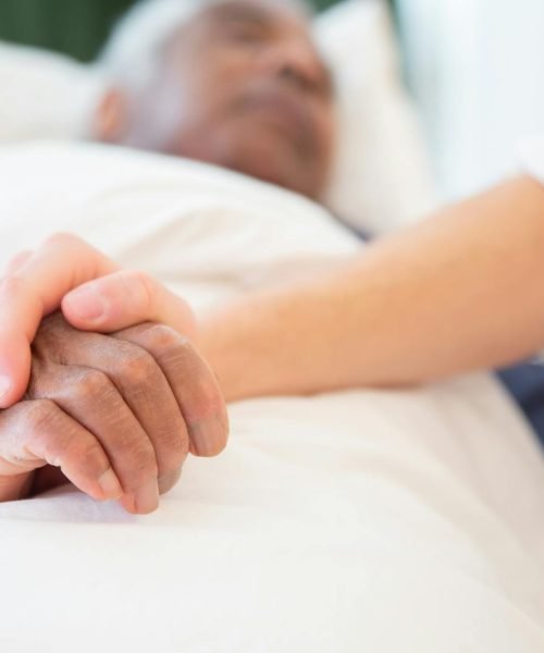A comforting gesture as a hand holds another in a hospital setting, symbolizing care and support.